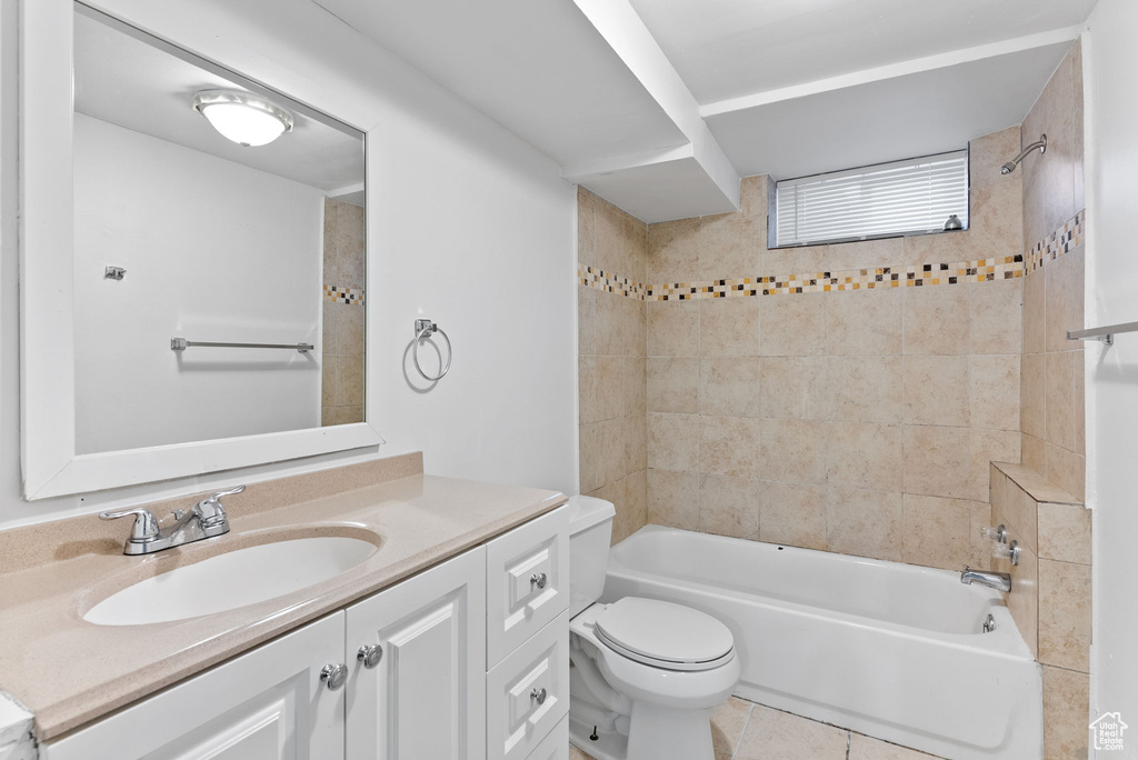 Full bathroom featuring toilet, tiled shower / bath combo, vanity, and tile patterned flooring