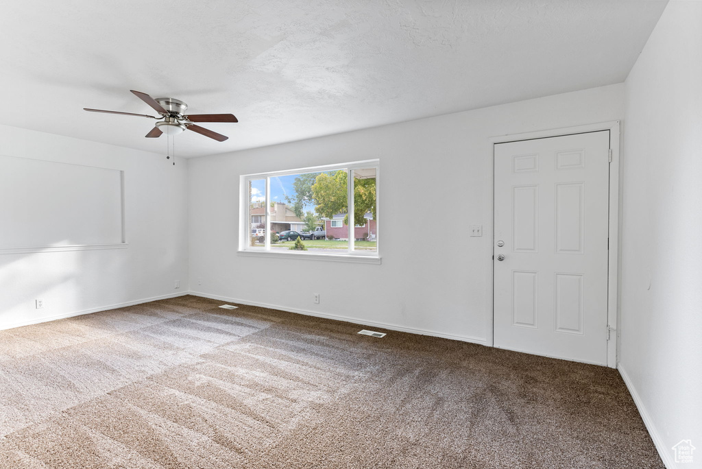 Carpeted empty room featuring ceiling fan