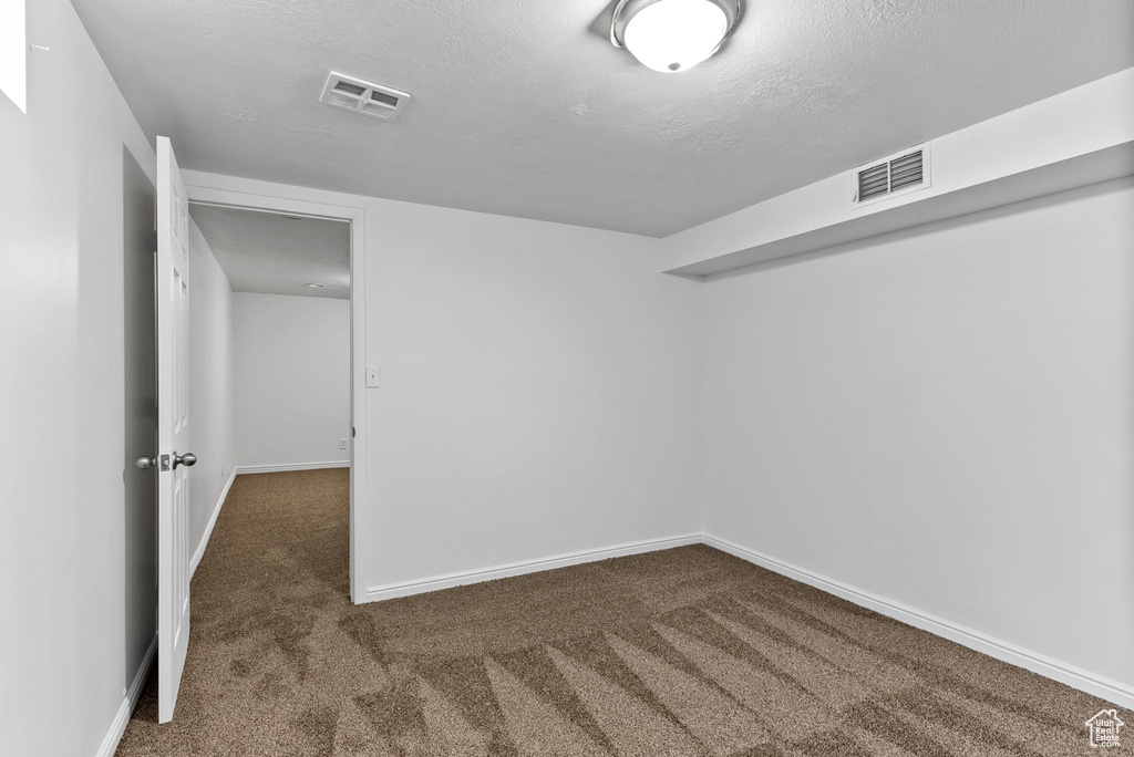 Spare room with a textured ceiling and dark carpet