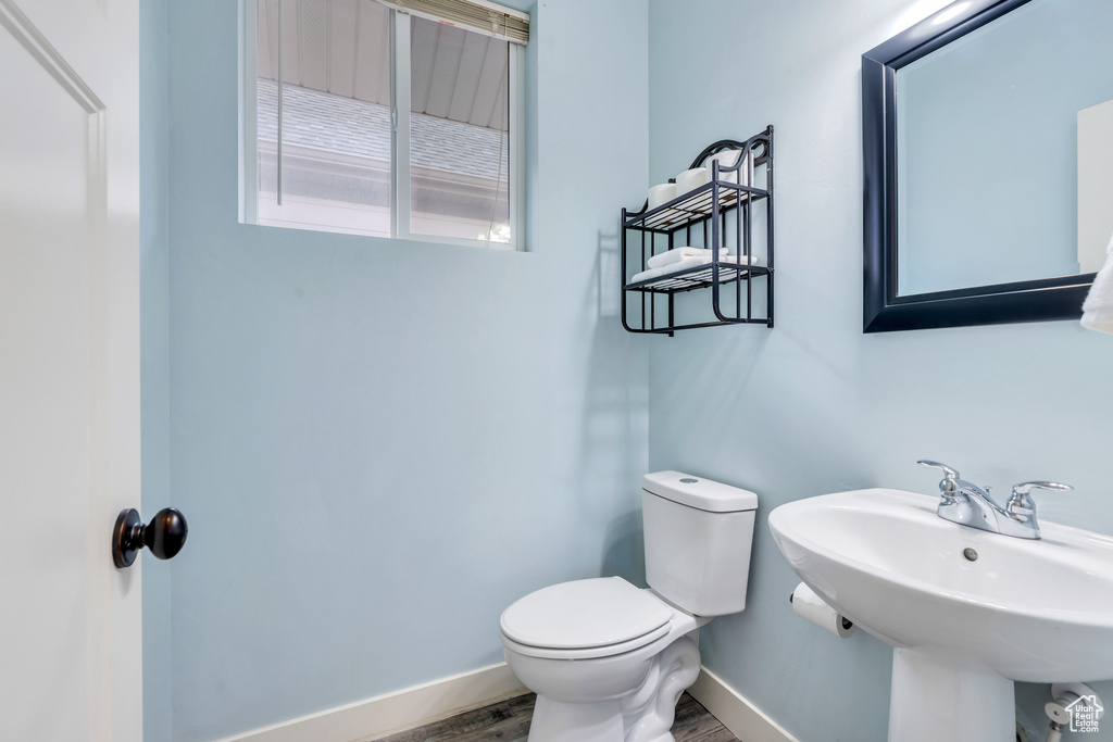 Bathroom featuring a sink, baseboards, toilet, and wood finished floors