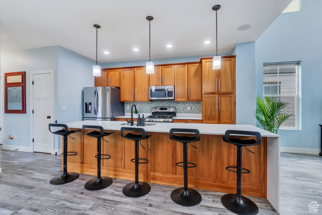 Kitchen featuring appliances with stainless steel finishes, light countertops, baseboards, a sink, and light wood-style flooring