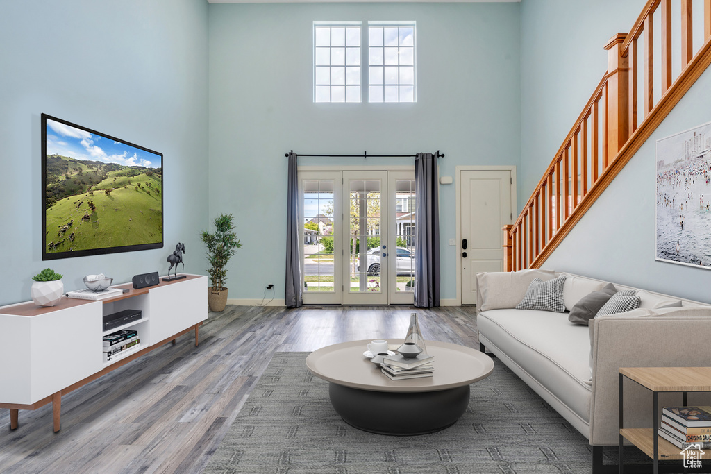 Living room with french doors, baseboards, wood finished floors, a towering ceiling, and stairway