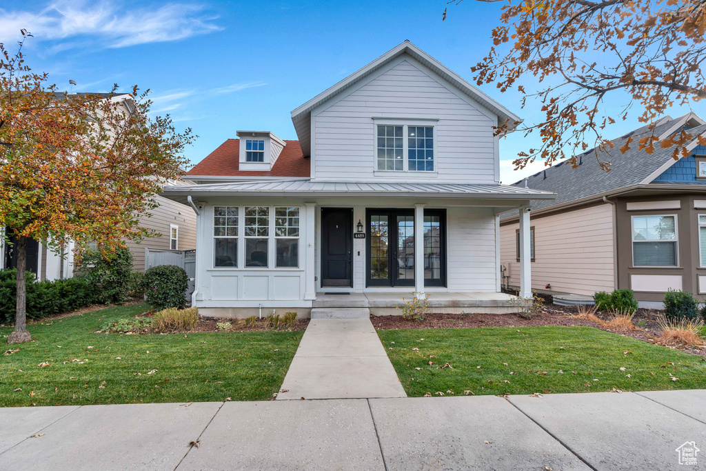 View of front of home featuring a standing seam roof, covered porch, metal roof, and a front lawn