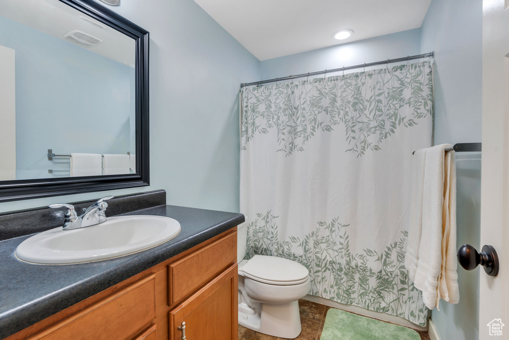 Full bath with toilet, visible vents, curtained shower, and vanity