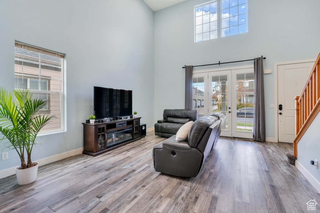 Living room featuring a high ceiling, a healthy amount of sunlight, stairway, and wood finished floors