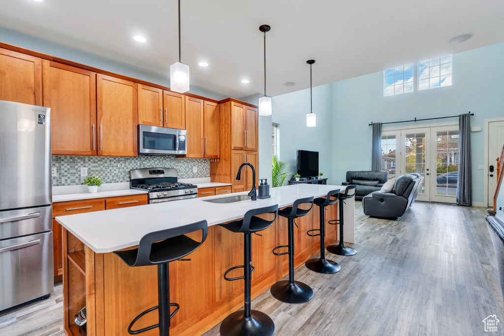 Kitchen featuring brown cabinetry, light wood-type flooring, a sink, light countertops, and stainless steel appliances