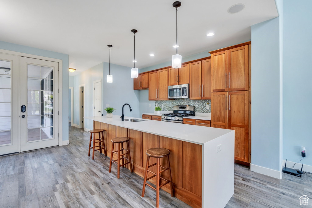 Kitchen with french doors, brown cabinets, light wood-type flooring, a sink, and stainless steel appliances