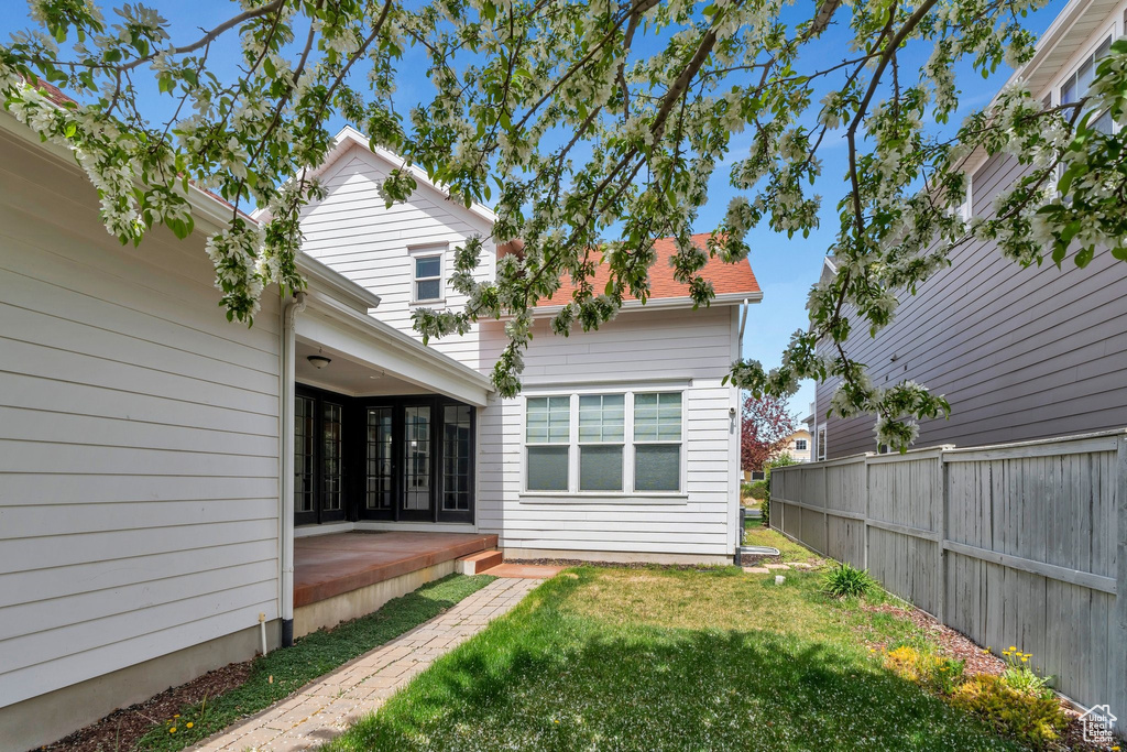 Rear view of property featuring fence, a patio, and a lawn