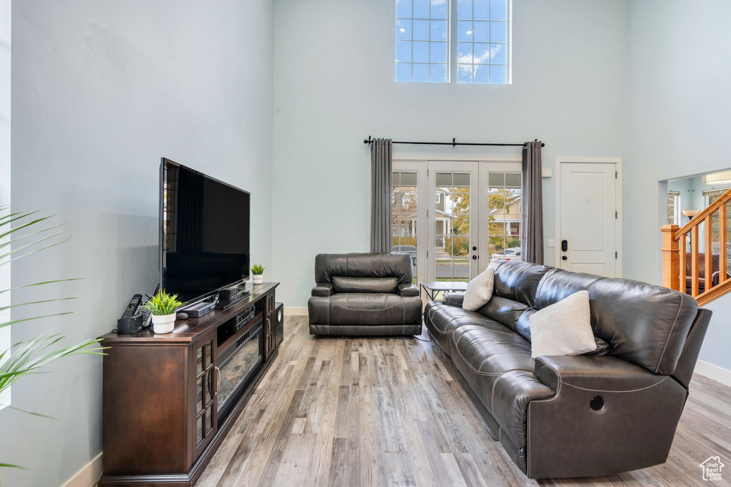 Living room featuring baseboards, light wood finished floors, stairs, and a towering ceiling