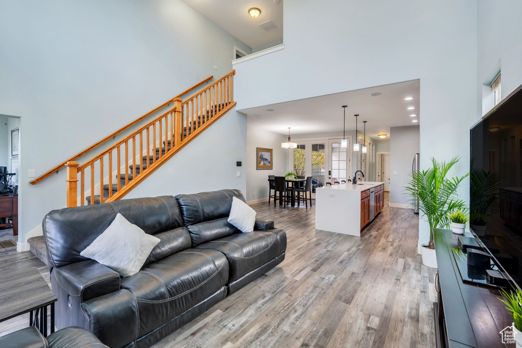 Living area featuring light wood-style floors, baseboards, stairs, and a towering ceiling