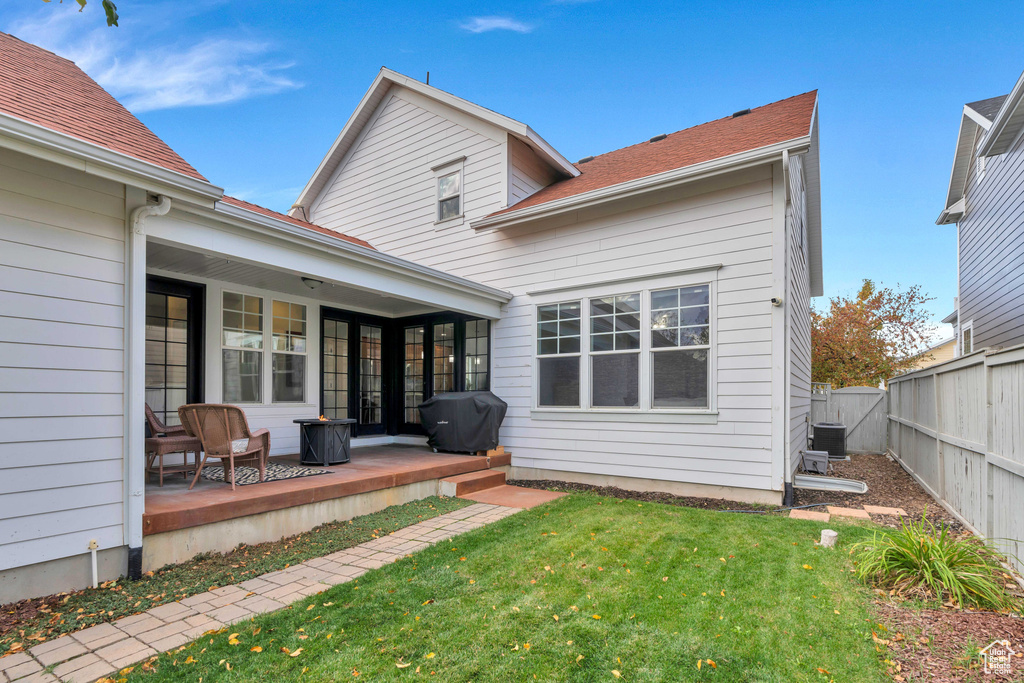 Back of house featuring a lawn, fence, and central AC unit