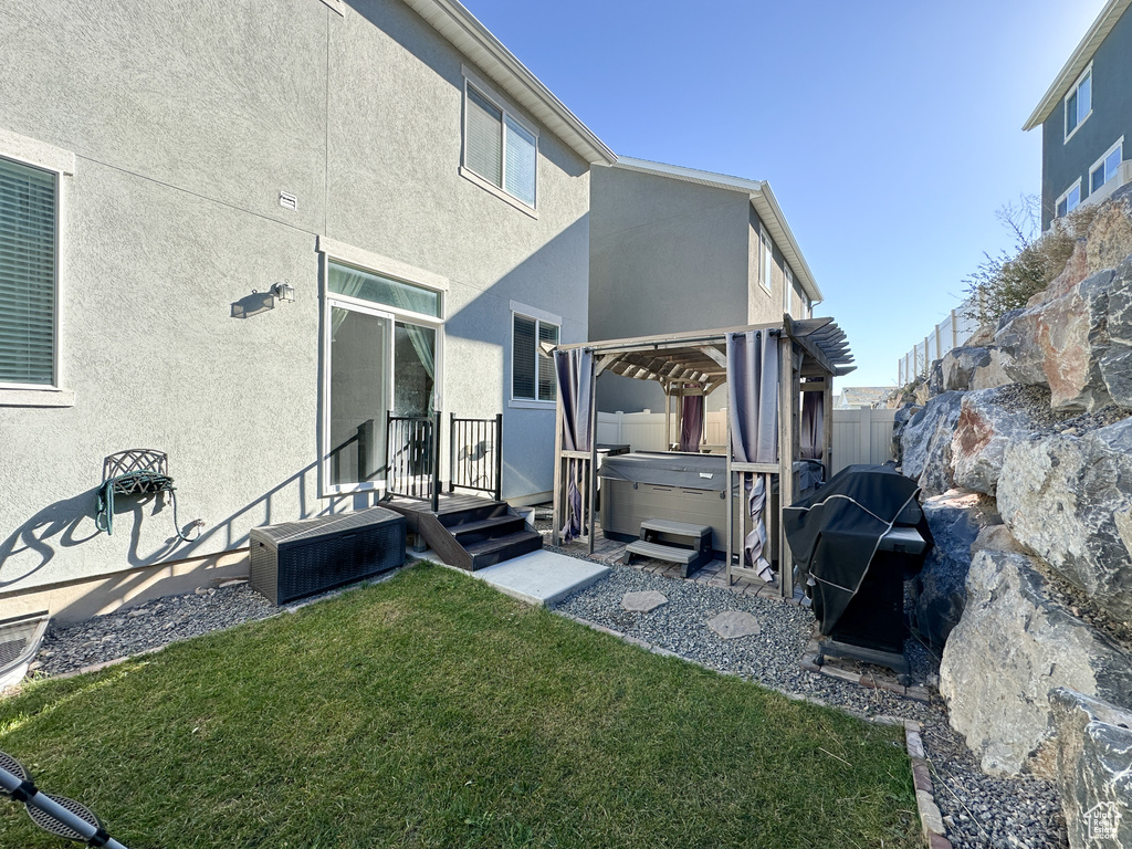 Rear view of property with a hot tub, a lawn, central AC unit, and a pergola