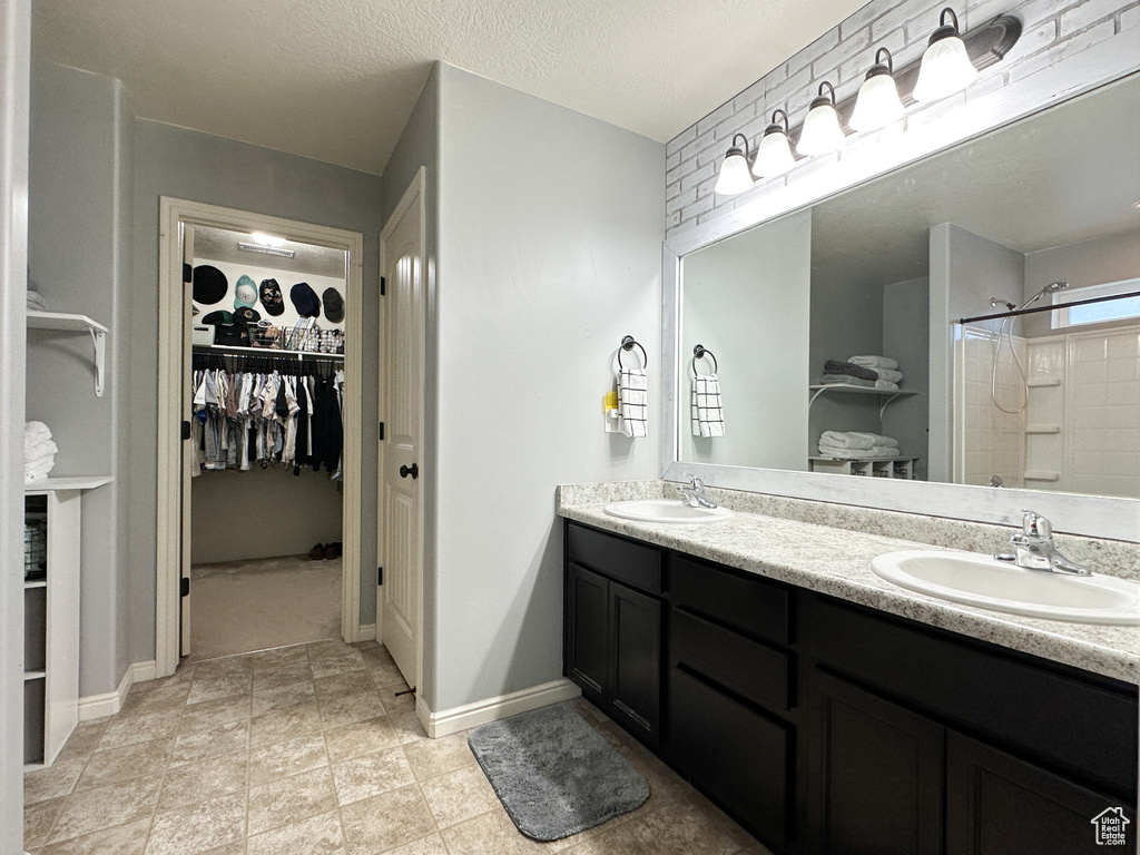 Bathroom featuring vanity, a textured ceiling, and walk in shower