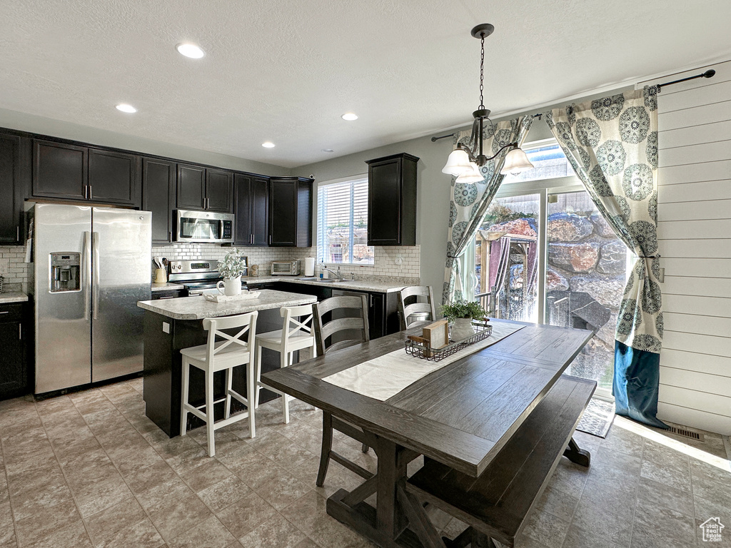 Dining room with sink, a textured ceiling, an inviting chandelier, and wooden walls