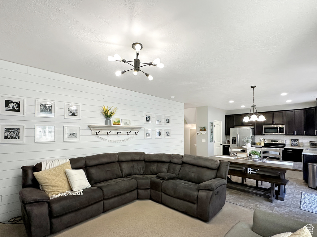 Living room featuring a notable chandelier, a textured ceiling, and wood walls