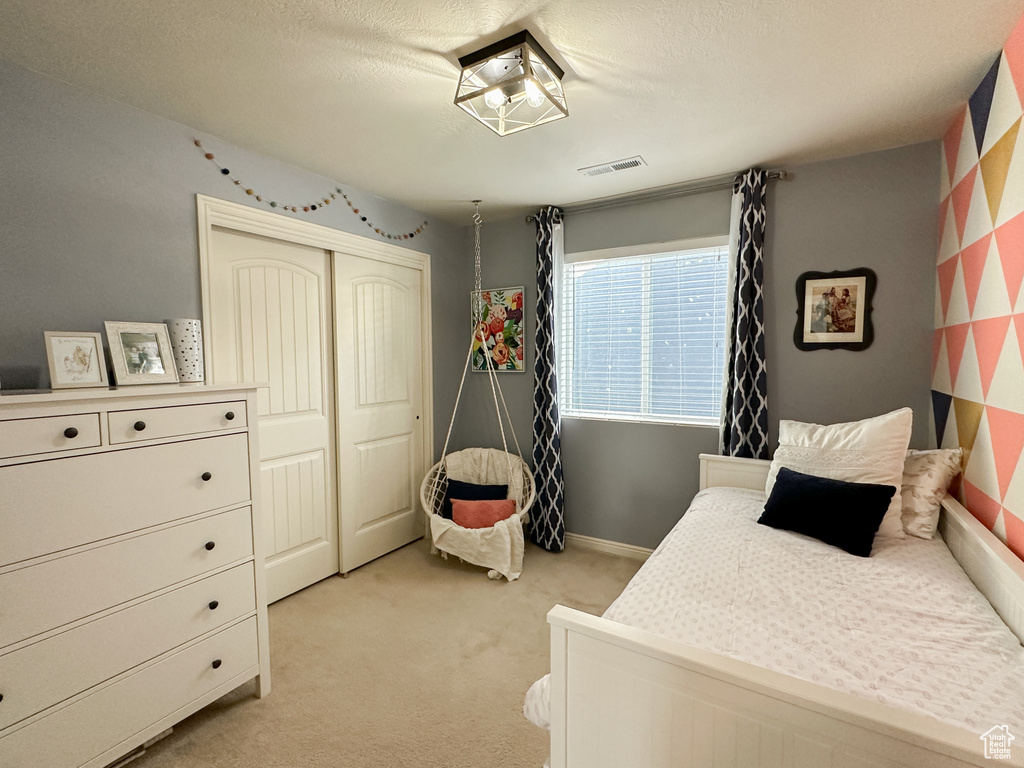 Carpeted bedroom with a textured ceiling and a closet