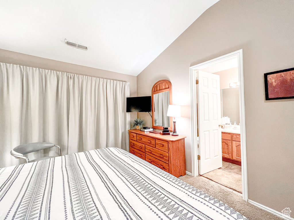 Carpeted bedroom featuring connected bathroom and lofted ceiling