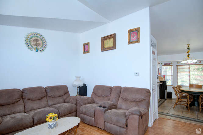 Living room featuring lofted ceiling, light hardwood / wood-style flooring, and a chandelier