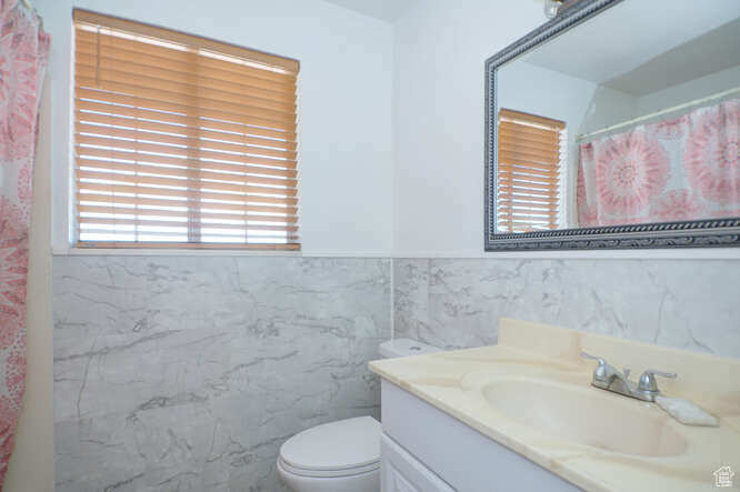 Bathroom with tile walls, vanity, and toilet