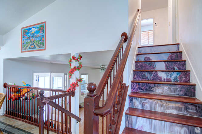 Staircase with vaulted ceiling, ceiling fan, and plenty of natural light