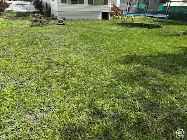 View of yard featuring a trampoline and fence