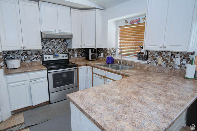 Kitchen featuring white cabinetry, sink, kitchen peninsula, and stainless steel electric range oven