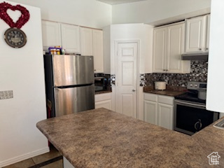 Kitchen featuring white cabinetry, kitchen peninsula, stainless steel appliances, and tasteful backsplash