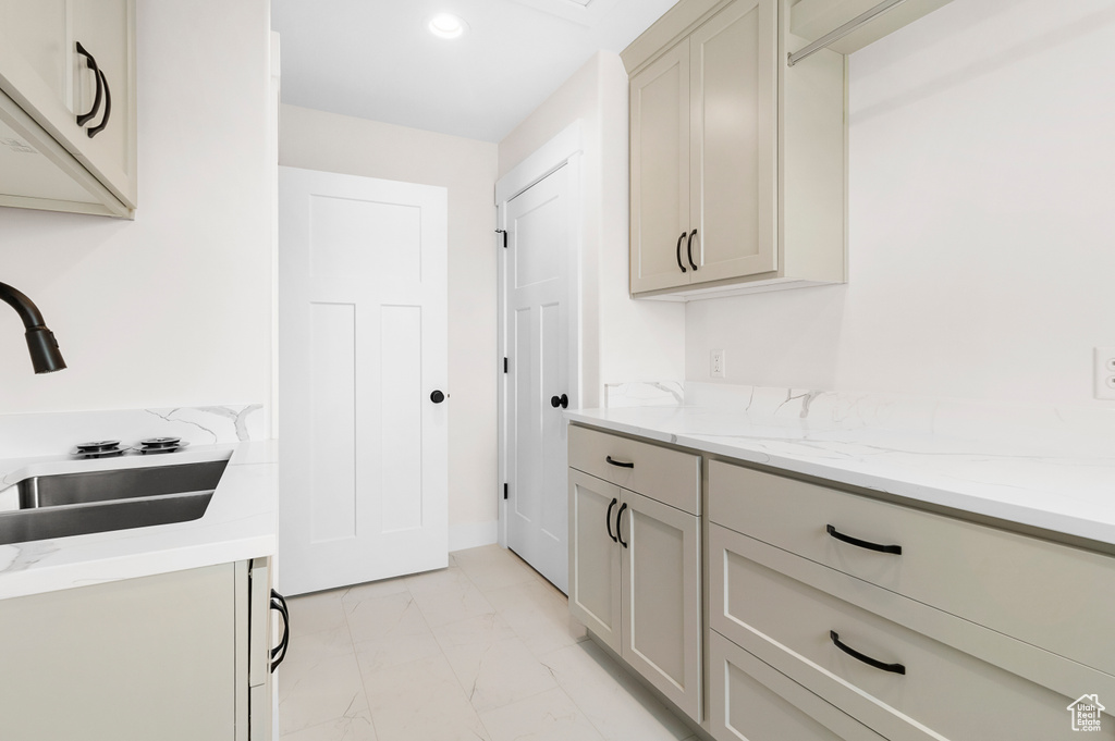 Kitchen with light stone countertops, marble finish floor, a sink, and recessed lighting