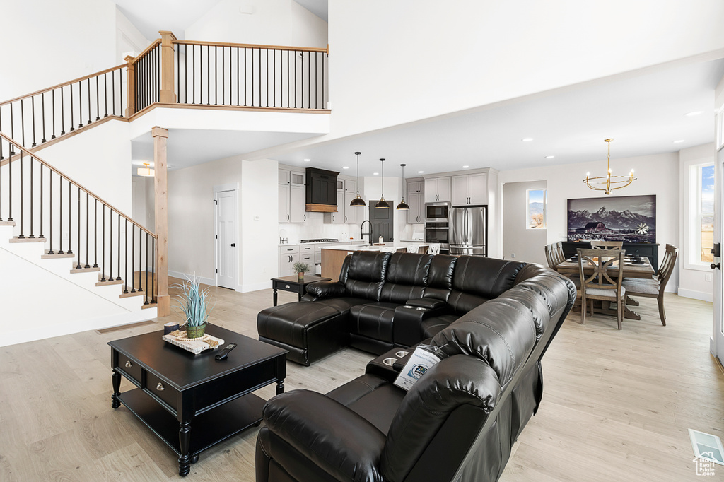 Living area featuring light wood-type flooring, stairway, and an inviting chandelier