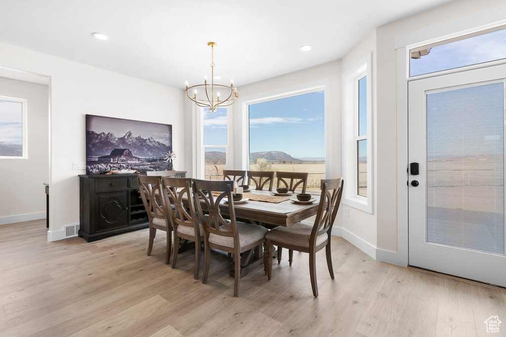 Dining space with a wealth of natural light, baseboards, light wood finished floors, and an inviting chandelier