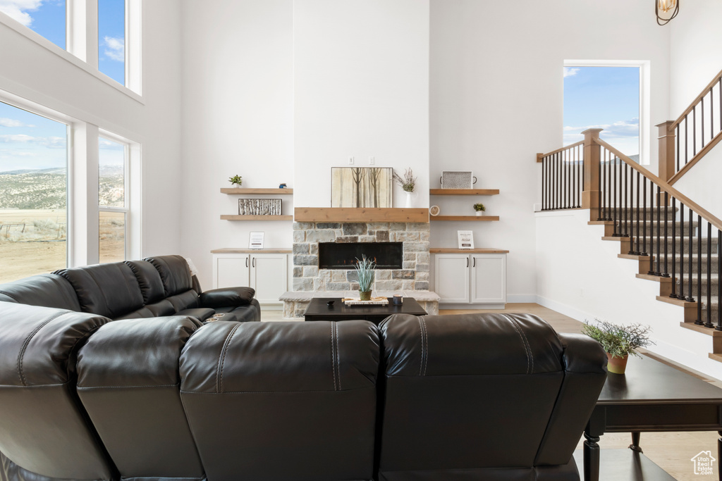 Living room featuring a fireplace, a high ceiling, wood finished floors, baseboards, and stairs