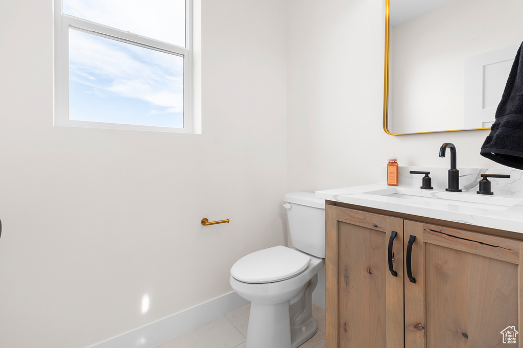 Bathroom with toilet, tile patterned flooring, baseboards, and vanity