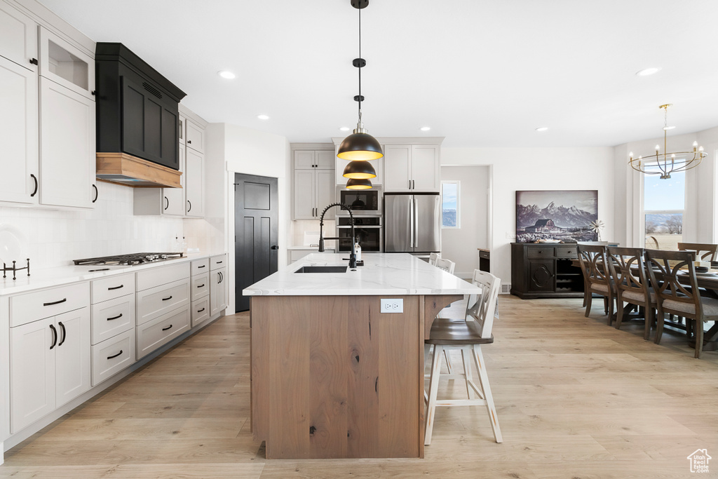 Kitchen featuring light wood-type flooring, a healthy amount of sunlight, stainless steel appliances, and a sink