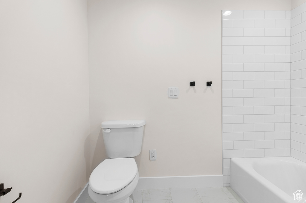 Bathroom featuring marble finish floor, toilet, and baseboards