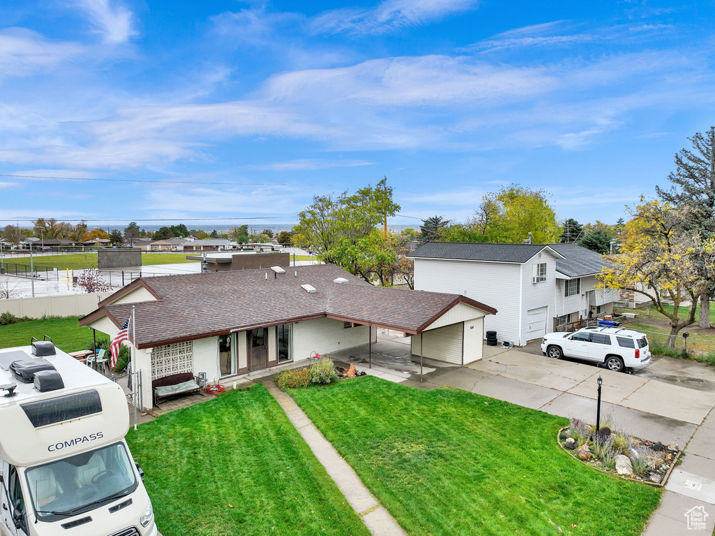 View of front of property with a front yard, a garage, and a carport