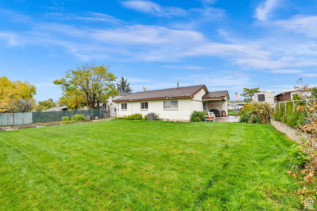 Back of house with cooling unit, a patio, and a lawn