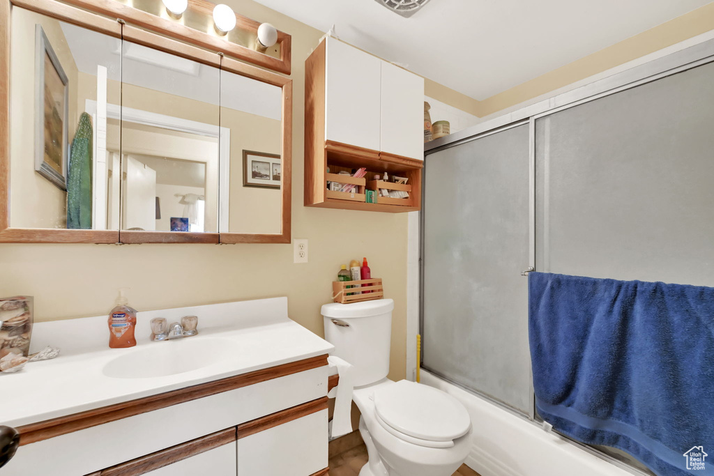 Full bathroom featuring vanity, toilet, and shower / bath combination with glass door