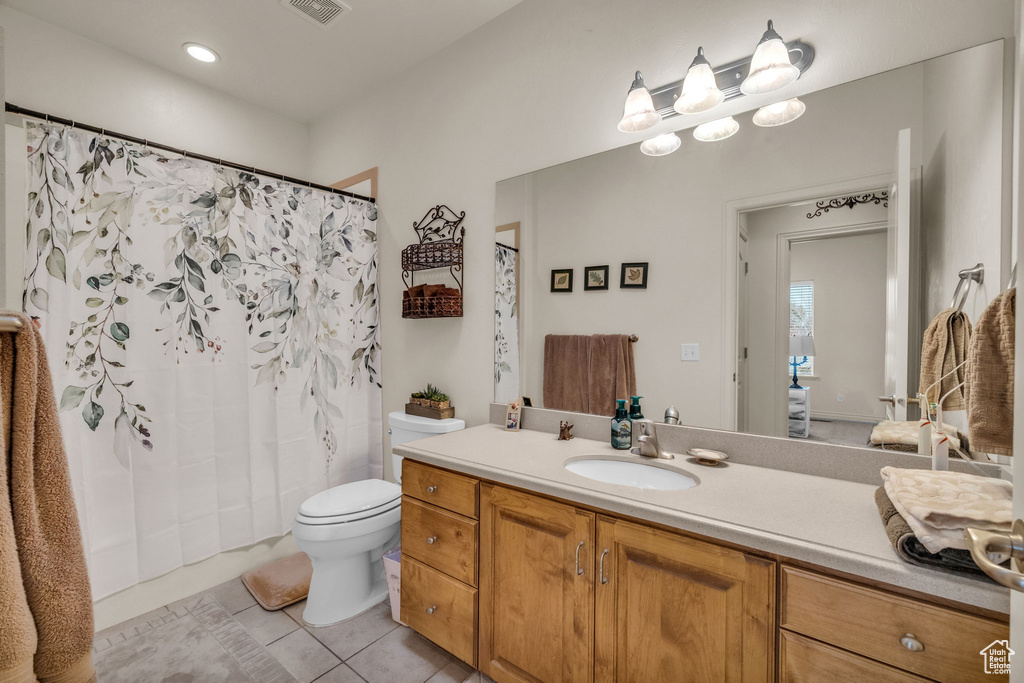 Bathroom featuring vanity, toilet, walk in shower, and tile patterned flooring