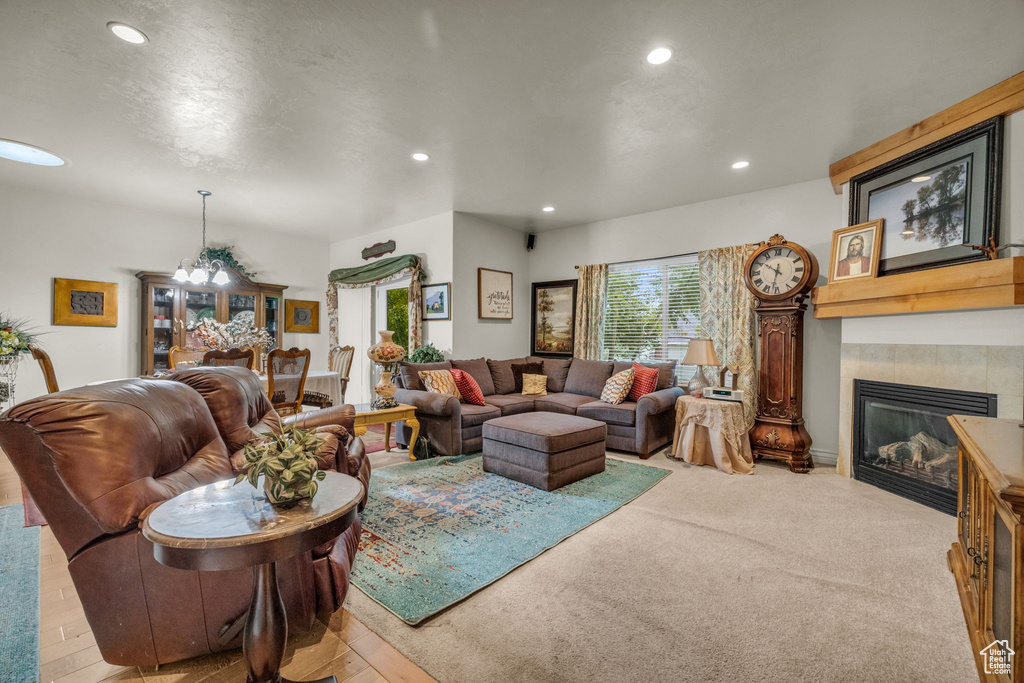 Carpeted living room featuring a fireplace and an inviting chandelier