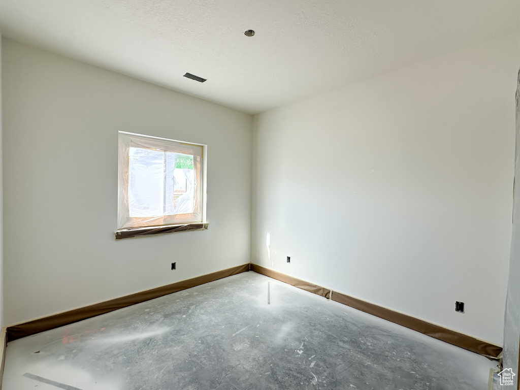 Spare room featuring a textured ceiling and concrete flooring