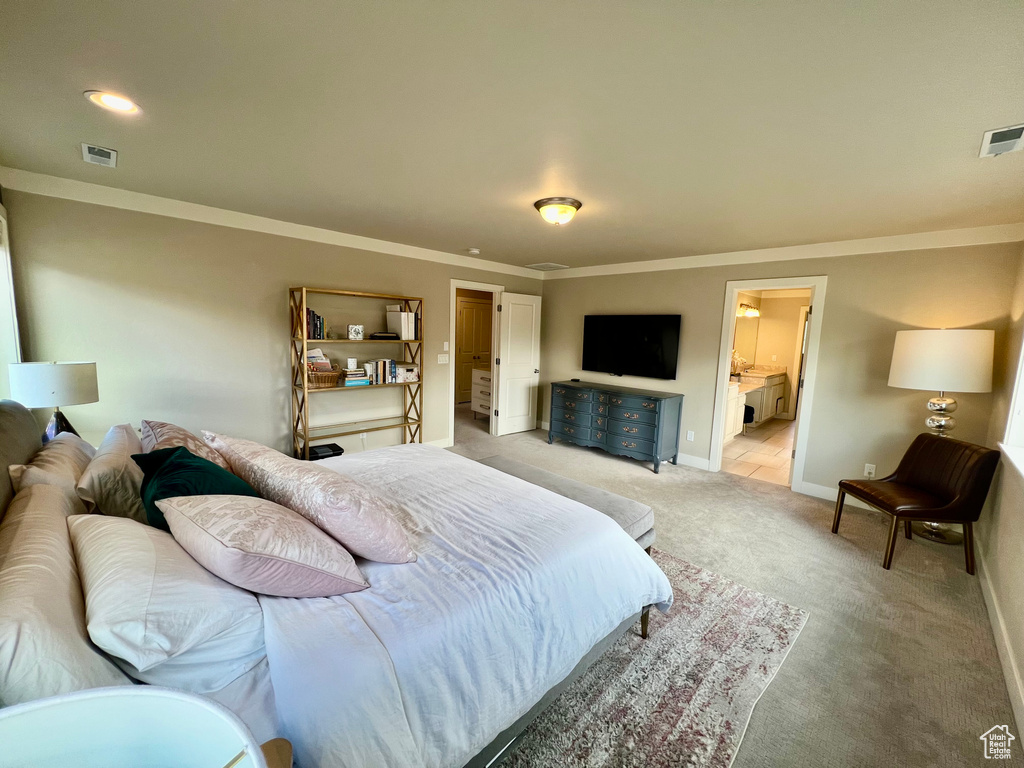 Bedroom featuring crown molding, light colored carpet, and ensuite bath