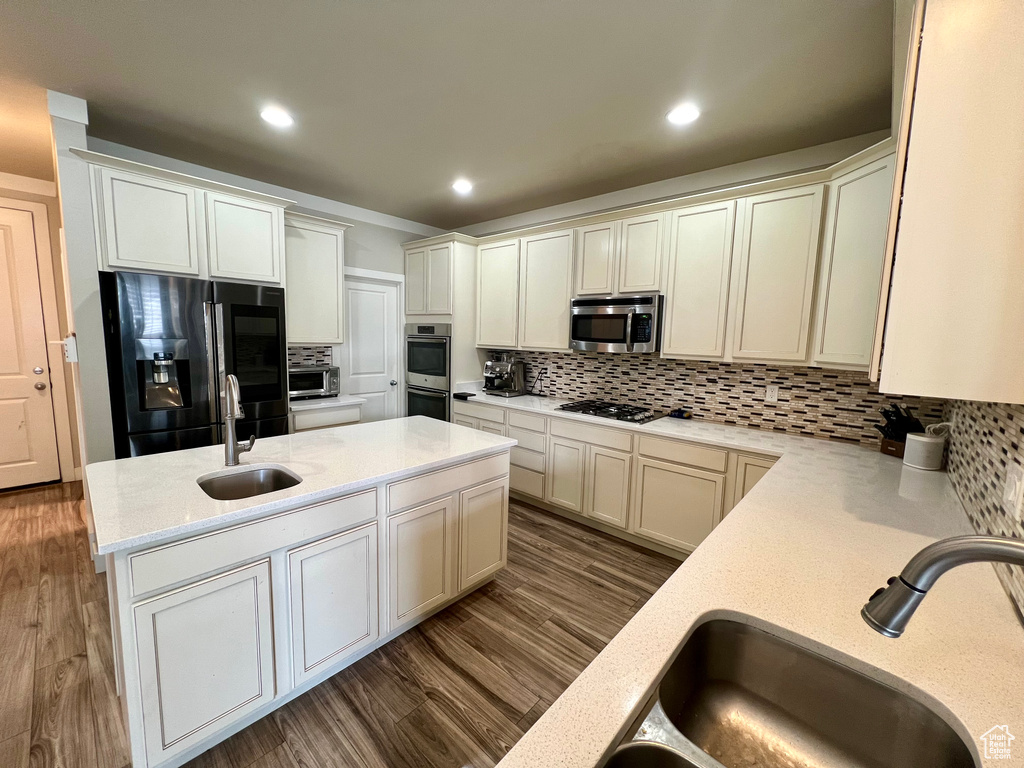 Kitchen featuring sink, dark wood-type flooring, stainless steel appliances, and backsplash