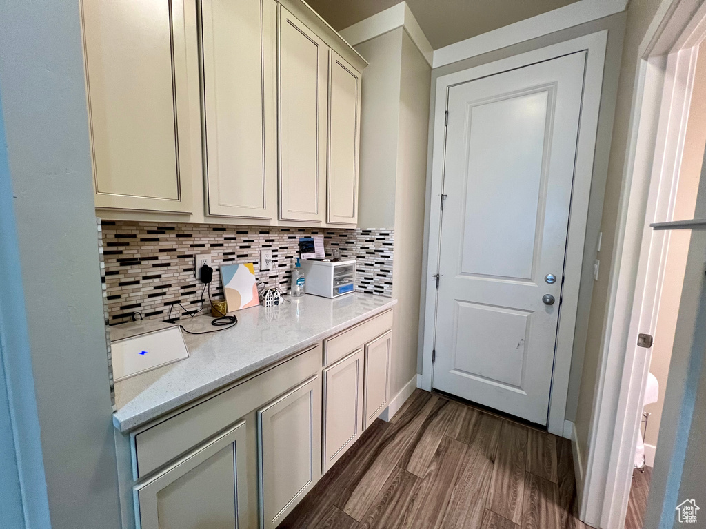 Interior space with dark wood-type flooring, backsplash, and light stone counters