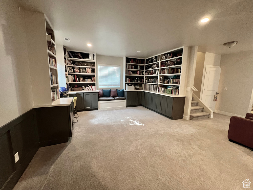 Home office with light colored carpet and built in shelves