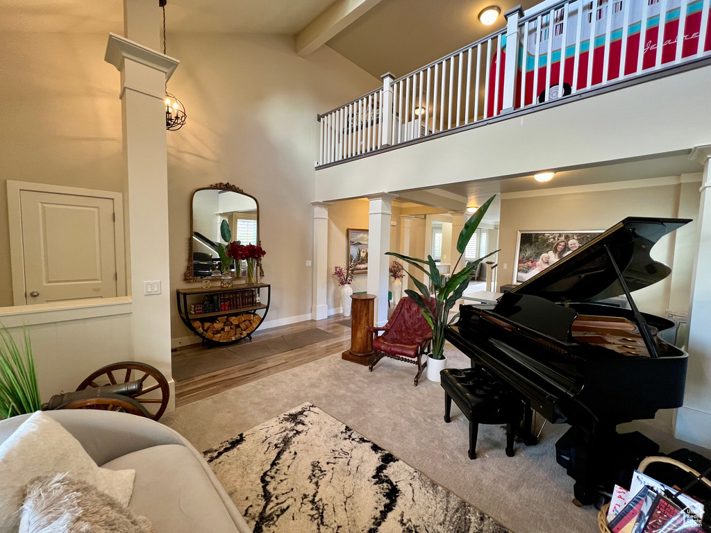 Interior space featuring hardwood / wood-style floors, decorative columns, beam ceiling, and high vaulted ceiling