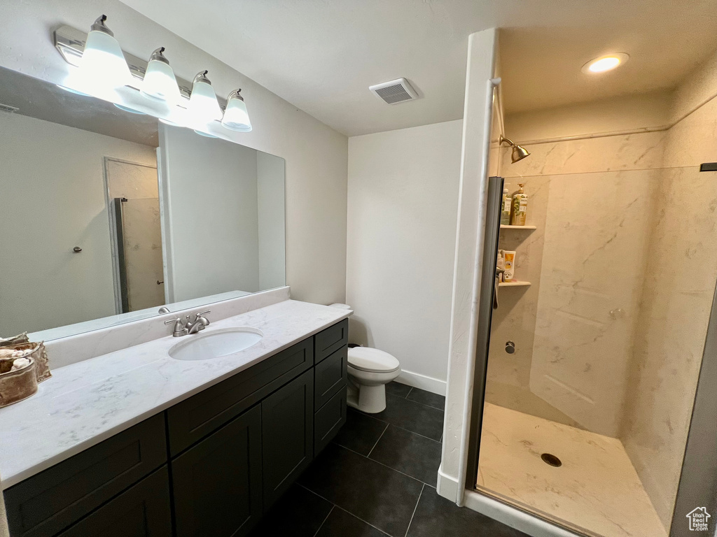 Bathroom with vanity, toilet, tile patterned flooring, and a shower with door