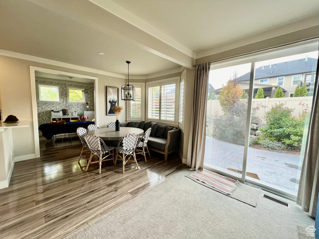 Dining space with beam ceiling, ornamental molding, and hardwood / wood-style floors