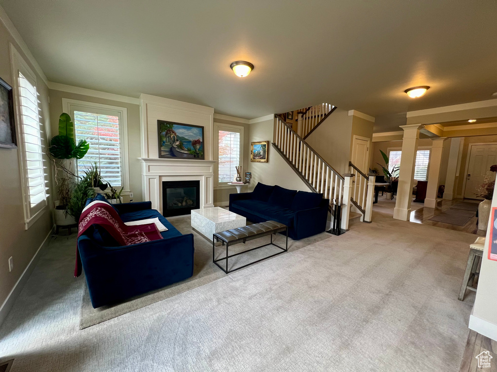 Living room with a large fireplace, decorative columns, and ornamental molding