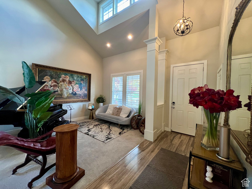 Entrance foyer with decorative columns, light wood-type flooring, high vaulted ceiling, and plenty of natural light