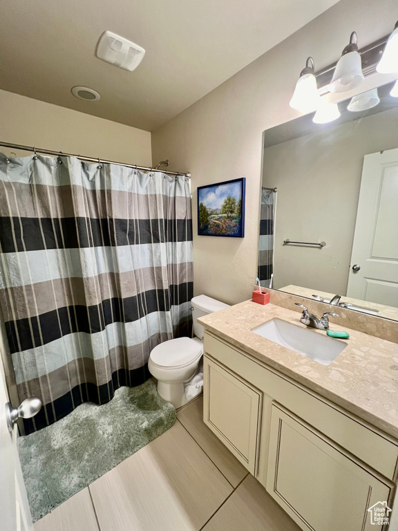 Bathroom featuring vanity, tile patterned flooring, toilet, and walk in shower